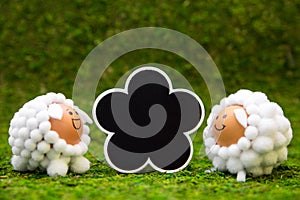 Cute selfmade lamb figures and slate on green meadow, concept spring and easter theme