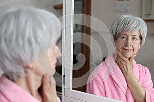 Cute senior woman looking at her reflection in the bathroom