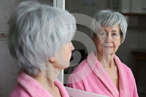 Cute senior woman looking at her reflection in the bathroom