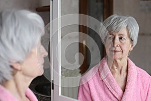 Cute senior woman looking at her reflection in the bathroom