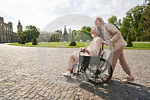 Cute senior woman pushing wheelchair with her partner