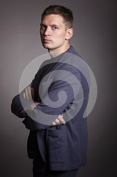 Cute serious young man in a jacket, gray background