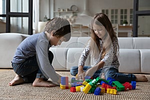 Cute sibling kids constructing toy tower, completing model