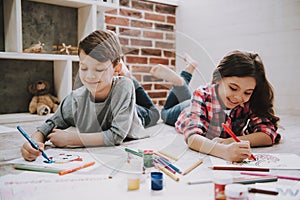 Cute Siblings Drawing Pictures Laying at Floor