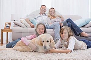 Cute siblings playing with dog with their parent on the sofa