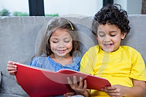 Cute siblings reading a book on the sofa