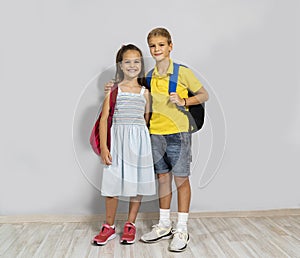 The cute siblings with school bags , gray background