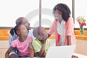 Cute siblings using laptop together with parents