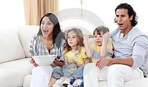 Cute siblings watching TV with their parents