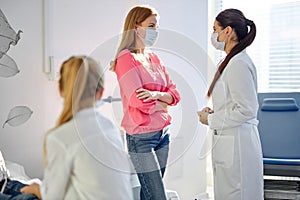 cute sick child girl sits looking at mother talking with doctor in hospital
