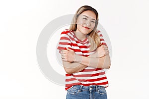 Cute silly asian girl blond haircut wearing summer striped t-shirt shrugging cute smiling cross arms chest feel chilly