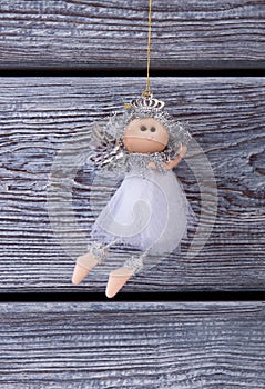 Cute silver fairy hanging on a wooden background.