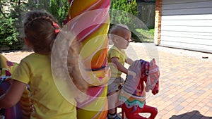 Cute sister and brother sitting on playground carousel. Gimbal motion