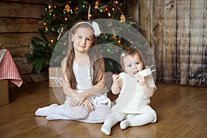 Cute sisters in front of decorated Christmas tree