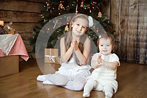 Cute sisters in front of decorated Christmas tree