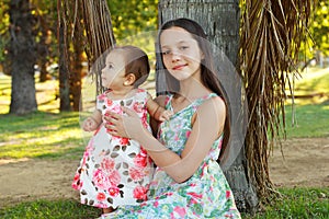 Cute sisters teen and baby girl playing on green grass