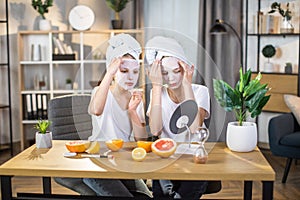 Cute sisters using mask on face during leisure time