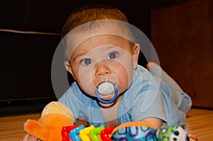Cute six months old baby boy playing on the flor with teething toy, early development and teething concept