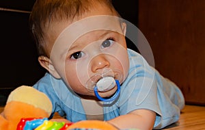 Cute six months old baby boy playing on the flor with teething toy, early development and teething concept