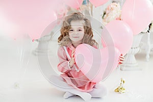 Cute six year old girl in pink dress with pink balloons in the shape of heart