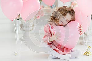 Cute six year old girl in pink dress with pink balloons in the shape of heart