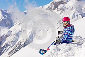 Cute ski girl portrait sit in snow on mountain top