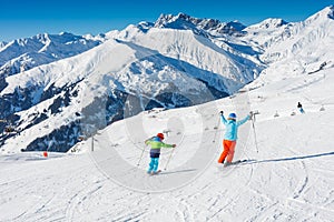 Cute skier boy with his mother having fun in a winter ski resort.