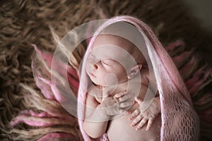 Cute sleeper newborn baby girl in pink on wool