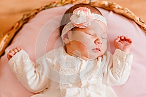 Cute sleeping baby girl in smart white dress and golfs lies on a round crib. photo shoot of newborns