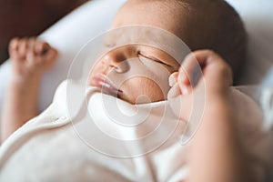 Cute sleeping baby wear white pajamas lying in crib close up. Healthy sleep. Childhood