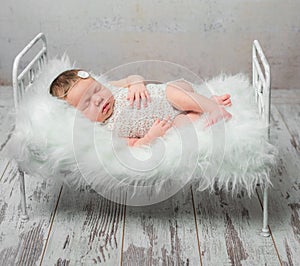 Cute sleeping newborn baby on cot with fluffy blanket