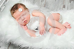 Cute sleeping newborn baby on cot with fluffy blanket
