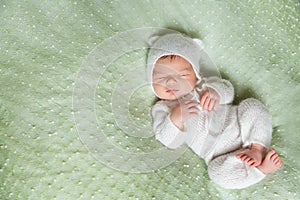 Cute sleeping newborn baby in white knitted fluffy kitten costume