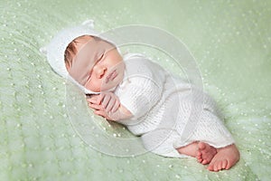 Cute sleeping newborn baby in white knitted fluffy kitten costume