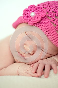 Cute sleeping newborn girl in pink hat, close-up
