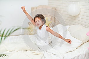 Cute sleepy baby girl, stretches, hands up, after sleeping in the morning