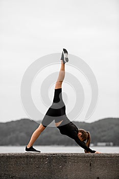 Cute slim fitness woman standing in downward dog pose with one leg up