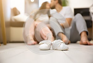 Cute Small babies shoes..Man hugs pregnant woman. Waiting for a baby birth. Happy family