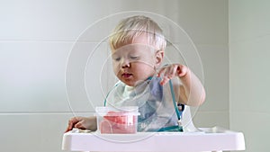 Cute small baby boy eating watermelon in kitchen