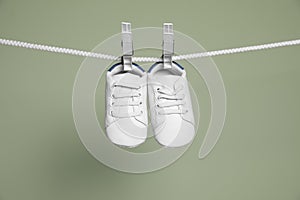 Cute small baby shoes hanging on washing line against green background