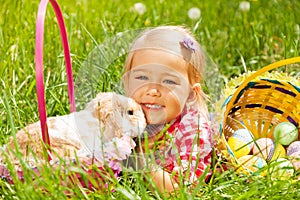 Cute small girl cuddling rabbit in field