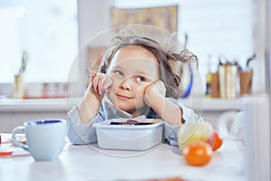 Cute small girl eating tasty lunch sitting at the table