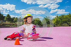 Cute small girl learn to skate rollers, sit in helmet and smile