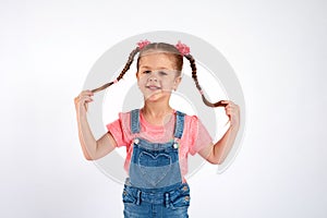 Cute small girl smailing and pulling her hair in the air, isolated on white background