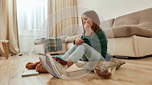 A cute small girl starring at a gamepad lying on her feet sitting on a floor in a middle of a spacy room