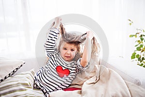 A small happy girl in striped T-shirt at home having fun.