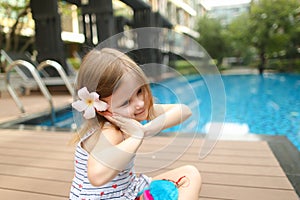 Cute small human girl kid sitting close to swimming pool wearing