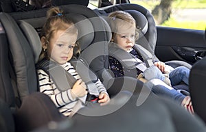 Cute small twins in car seats in the car