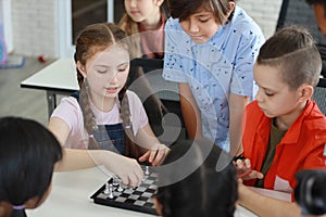 Cute and smart kids playing chess in class education concept