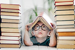 Cute smart preschool girl reading books in library or at home. Kids early learning and home education concept